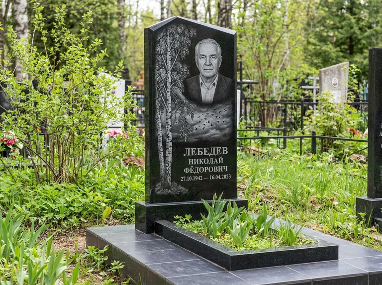 Памятник с гравировкой берёзы: вертикальная стела со скошенным верхом — берёза и стая птиц в небе, гранитный цоколь с тёмной плиткой, работа «Лебедев» в Сочи