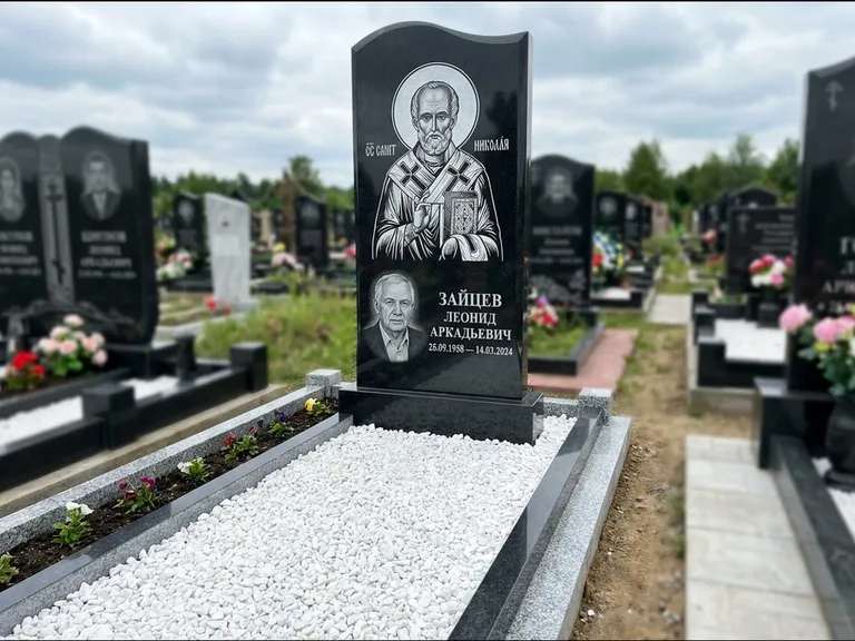 Памятник с гравировкой иконы: стела с крестообразным навершием — икона в резной рамке-киоте, газон без ограды, стриженая трава, работа «Раевская» в Сочи