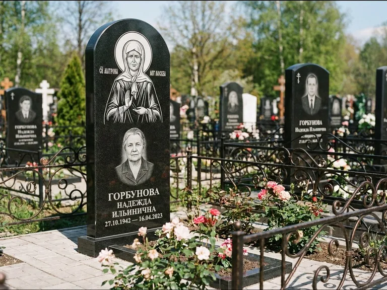 Памятник с гравировкой иконы: стела с арочным верхом и киотом под образ — гравировка образа Матроны Московской, гранитный цоколь с тёмной плиткой, работа «Ковалёв» в Сочи