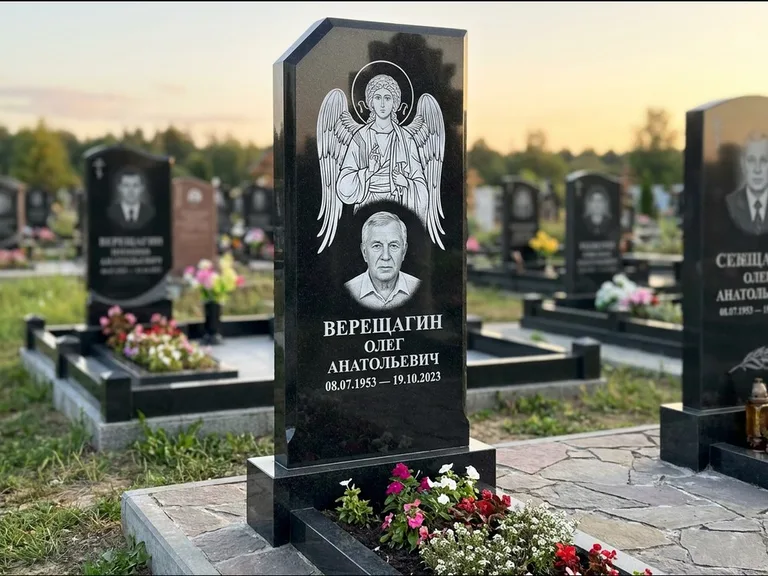 Памятник с гравировкой иконы: стела с резным навершием и нимбом в золоте — гравировка образа Спасителя, высокие разросшиеся туи полукругом, работа «Мельникова» в Сочи