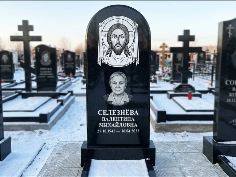Памятник с гравировкой иконы: небольшая скромная одиночная стела с именной иконой — золочёный нимб на образе, аккуратный участок с газоном, работа «Ковалёв» в Сочи