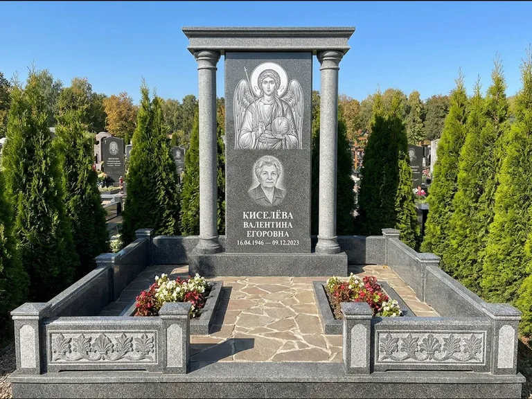 Памятник с гравировкой иконы: массивная стела с двускатным навершием-домиком — гравировка Николая Чудотворца, живая изгородь из туи, работа «Журавлёв» в Сочи