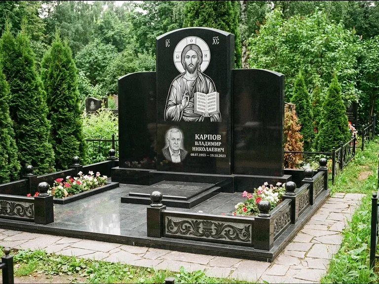 Памятник с гравировкой иконы: широкая панорамная стела с золочёным нимбом — гравировка образа Матроны Московской, цветник с белыми хризантемами, работа «Мельникова» в Сочи